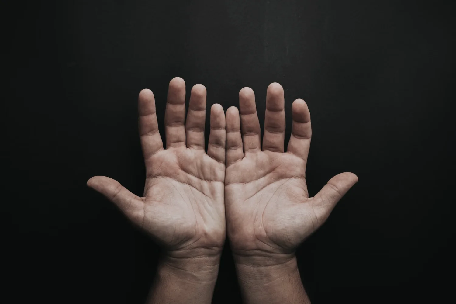 Two open hands offered against a dark background