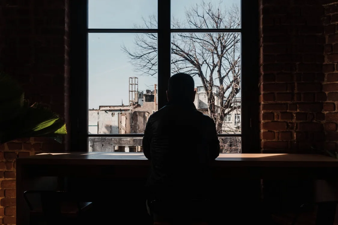 A solitary person sitting quietly in front of a window